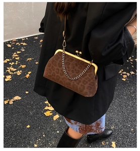 Sac coquille léopard avec fermoir à baiser et chaîne dorée porté sur un blazer noir