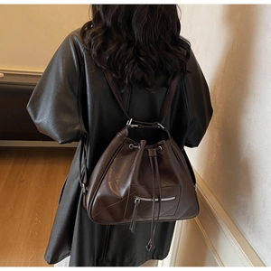 Detail view of deep brown quilted leather backpack with drawstring closure and silver hardware
