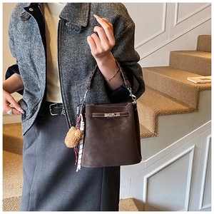 Detail of dark brown suede bucket bag featuring silver twist lock and chic bear charm
