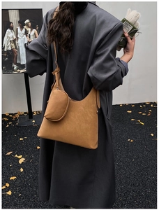 Brown suede hobo bag with matching zipper pouch shown on a model in an urban autumn setting