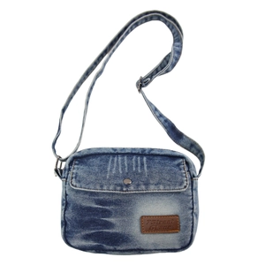 Détail d'un sac bandoulière en denim bleu avec poche frontale et écusson en cuir marron