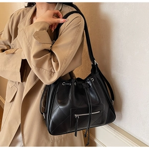 Detail of black quilted bucket bag with drawstring closure and silver-tone metal eyelets