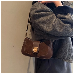 Detail of dark brown retro underarm bag with suede leather and gold oval twist lock