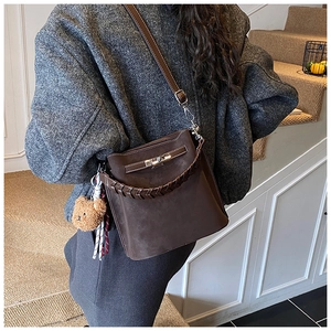 Brown suede bucket bag with woven handle, silver lock and cute bear charm on model