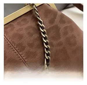 Vue macro de la quincaillerie dorée mate et des coutures sur un sac vintage en daim brun