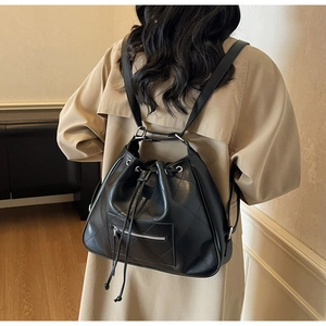 Detail of a large black quilted leather backpack with drawstring closure and silver zipper
