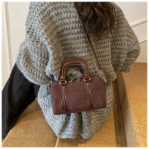 Close-up of retro brown suede handbag featuring embossed texture and top dual zippers