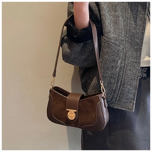 Detail of dark brown leather and suede stitching on underarm bag with gold hardware