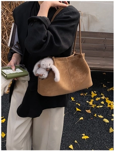 Brown frosted leather tote bag with white rabbit plush pendant in autumn setting