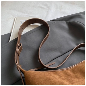 Vue détaillée d'un sac bandoulière en daim marron avec sangle réglable et boucle en métal