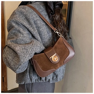 Close-up of brown suede and PU leather shoulder bag with vintage gold circular lock
