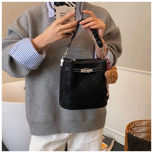 Detail of black suede bucket bag with woven handle and silver twist-lock closure