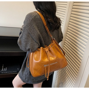 Detail of warm brown quilted bucket bag with zipper pocket worn by a model