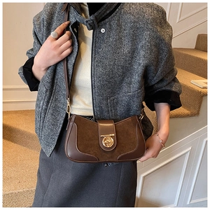 Detail of vintage brown suede leather half moon bag with gold clasp on grey tweed coat