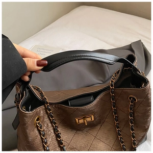 Detail of dark brown quilted tote bag with gold twist-lock closure and chain strap