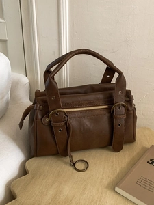 Sac Boston vintage en cuir PU marron avec boucles en laiton sur table en bois
