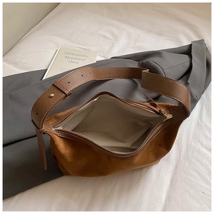 Sac sous le bras minimaliste en daim marron avec large bandoulière sur costume gris