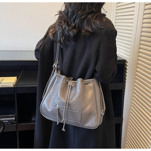 Detail of grey quilted bucket bag with drawstring closure and front zipper pocket