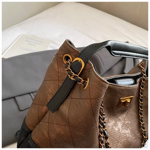 Detailed macro view of the brown quilted leather texture and gold chain strap of this bag