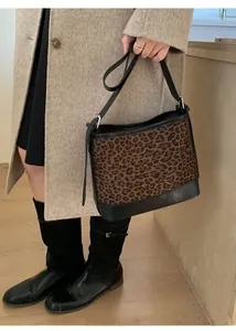 Close-up of leopard print shoulder bag with black leather trim on model with light coat