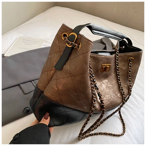 Detail of quilted tote bag with brown and black stitching and gold metal twist lock