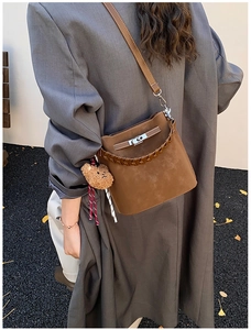 Detail of vintage suede bucket bag featuring metallic turn-lock and woven handle on model