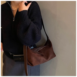 Modèle portant un sac hobo en daim marron avec bandoulière large et fini mat