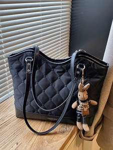 Sac cabas noir matelassé avec charme de lapin et texte FASHION BAG sur un rebord