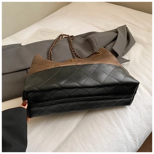 Detail of two-tone quilted leather tote with elegant gold chain strap and stitching