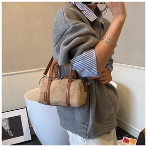 Detail view of khaki suede Boston bag with brown leather handles and adjustable strap