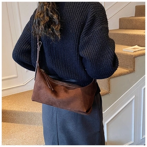 Détail du sac bandoulière en daim marron foncé avec fermetures éclair à franges sur modèle