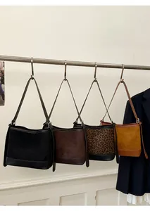Detail view of suede and leather bucket bags in black, brown, leopard, and yellow tones