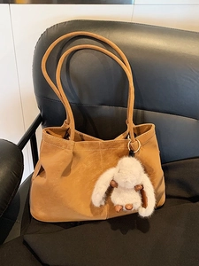 Brown leather tote bag with long shoulder straps and a cute white rabbit keychain