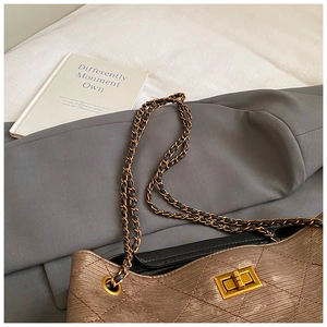 Close-up of champagne gold quilted texture fabric with elegant gold twist lock and chain