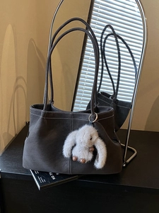 Minimalist dark grey tote bag with white contrast stitching and plush rabbit charm