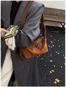 Détail d'un sac hobo en daim marron avec fermeture éclair et large bandoulière réglable