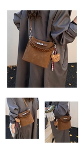Detail of vintage brown suede bucket bag featuring leather handle and bear charm
