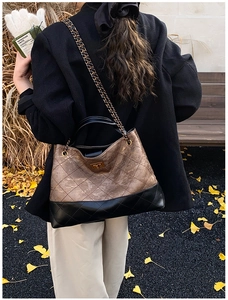 Detail of quilted chain tote bag with bronze and black contrast and metallic twist lock