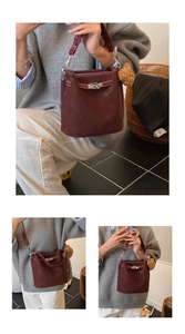 Macro shot of silver metal twist-lock closure on deep burgundy leather bucket bag