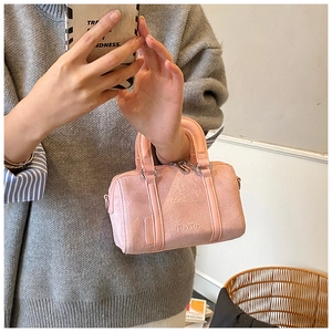 Detail of pink faux suede boston bag featuring relief character design and top handle