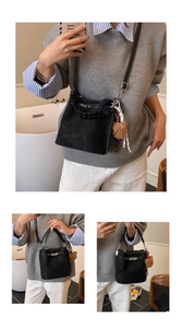 Detail of black suede bucket bag featuring woven handle and cute bear charm accessory