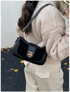 Close-up of minimalist black leather underarm bag featuring a metallic gold ring buckle