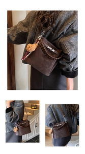 Detail of dark brown suede bucket bag with woven handle and silver twist lock