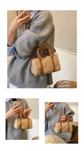 Detail of Boston-style canvas crossbody bag featuring brown leather trim and top handles
