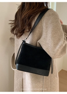 Retro black suede shoulder bag styled with a beige wool coat for a minimalist chic look