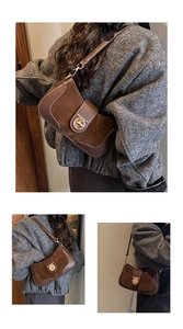 Detail of vintage brown leather shoulder bag featuring a round gold twist lock buckle