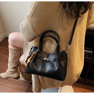 Detail of black textured PU leather handbag with silver twist lock and wooden bead charm