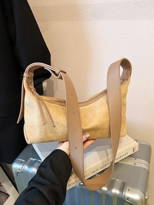 Sac oreiller en daim marron avec large bandoulière et franges tenu à la main