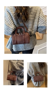 Detail of a brown frosted leather boston handbag with contrast trim and shoulder strap