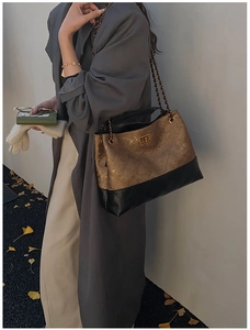 Detail of quilted two-tone tote bag with gold metallic twist lock and chain strap